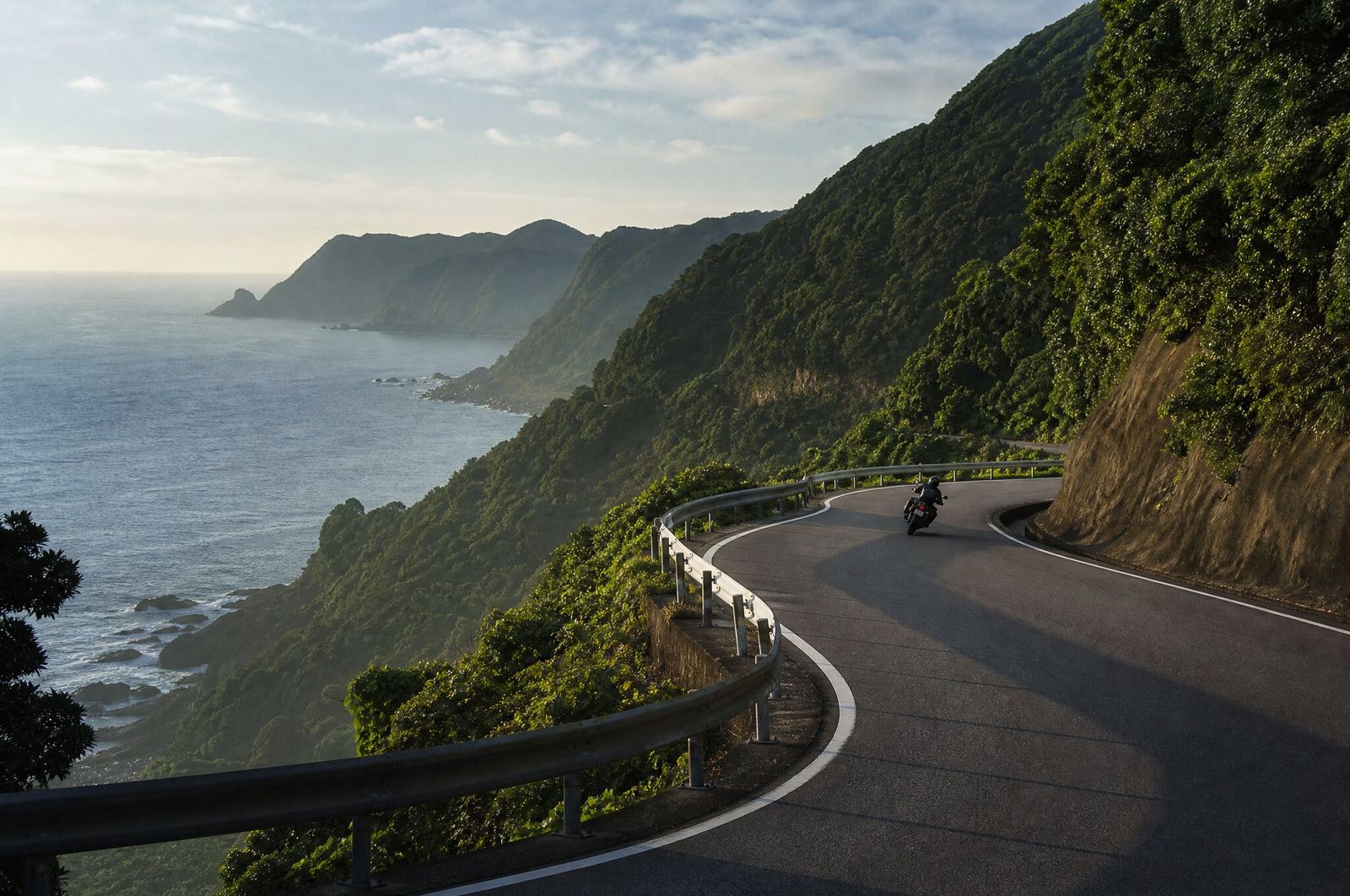 海を見下ろす緑の山肌を縫う、ワインディングの海岸線道路